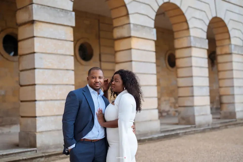 A couple smiling together beneath a stone archway. CameraBoss portfolio: Oney Prewedding at Boughton House.