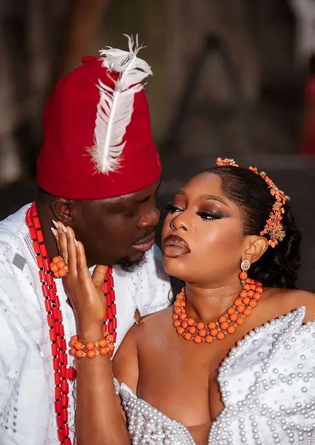 A close portrait of a couple in white attire and coral-coloured jewellery. CameraBoss portfolio: Korede Prewedding.