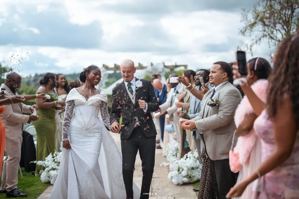 Helen and Jack walking between their guests with confetti in the air after the outdoor ceremony