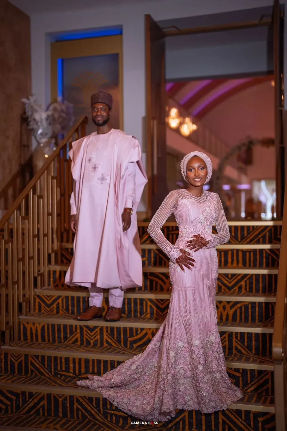 Elegant wedding fashion photoshoot featuring traditional white and pink embellished formal attire against wooden railings.